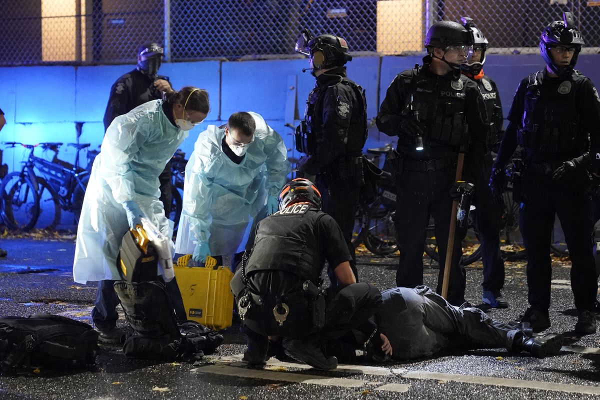Emergency crews attend an injured man detained by police during a protest after the Nov. 3 elections in front of the East Precinct station on Wednesday in Seattle’s Capitol Hill neighborhood.  (Associated Press)