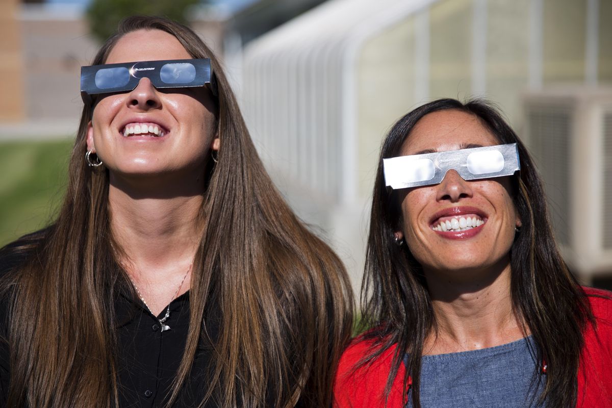 In this Tuesday, July 18, 2017, photo, Ashley Moretti, left, and Candace Wright use their eclipse shades to look at the sun as they pose for a portrait at Twin Falls High School in Twin Falls, Idaho. (Pat Sutphin / Times-News)