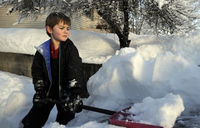 Cub Scout Jac Newman, 6, helps shovel snow off a car while clearing a driveway as a service project with the local Boy Scout community last week. (Jesse Tinsley / The Spokesman-Review)