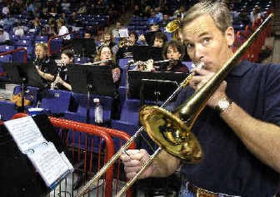
Russ Dingman tries to play the trombone and watch the A/C-H girls play King's West at the same time Wednesday afternoon at the WIAA State B tournament. Parents filled in for the band at the Spokane Arena and split time between playing music and cheering on kids. 
 (Christopher Anderson/ / The Spokesman-Review)