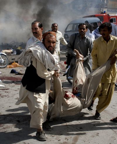 People carry a man injured by an explosion during a Shiite procession in Quetta, Pakistan, on Friday. Suicide bombings targeting religious minorities killed scores of people in Pakistan this week.  (Associated Press)