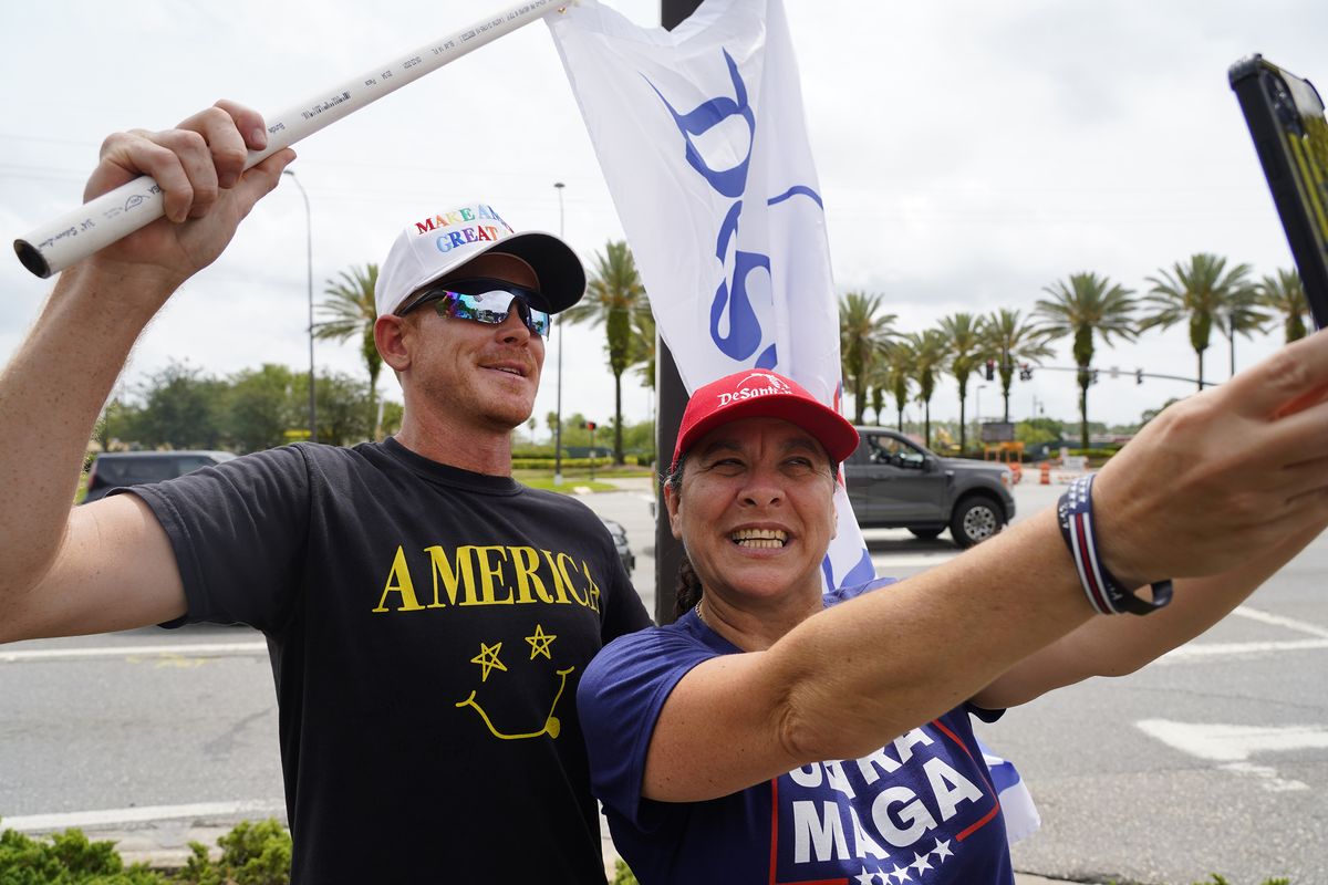 David Leatherwood, known online as Brokeback Patriot, poses with Pam Lathrop, 53, of North Port during a rally on May 21, 2022, in Orlando, Florida, outside of Walt Disney World. His flag reads, "DeSantisland." (Luis Santana/Tampa Bay Times/TNS)  (Luis Santana/Tampa Bay Times/TNS)