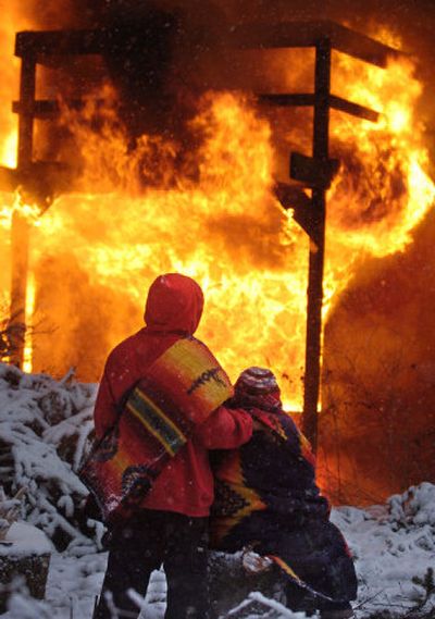 Nooksack Tribe spiritual elder Dorthy Charles, left,is comforted by her grandson Jasper Charles, left, while they watch a former drug house burn to the ground on the Lummi reservation near Bellingham on Thursday.
(Associated Press / The Spokesman-Review)