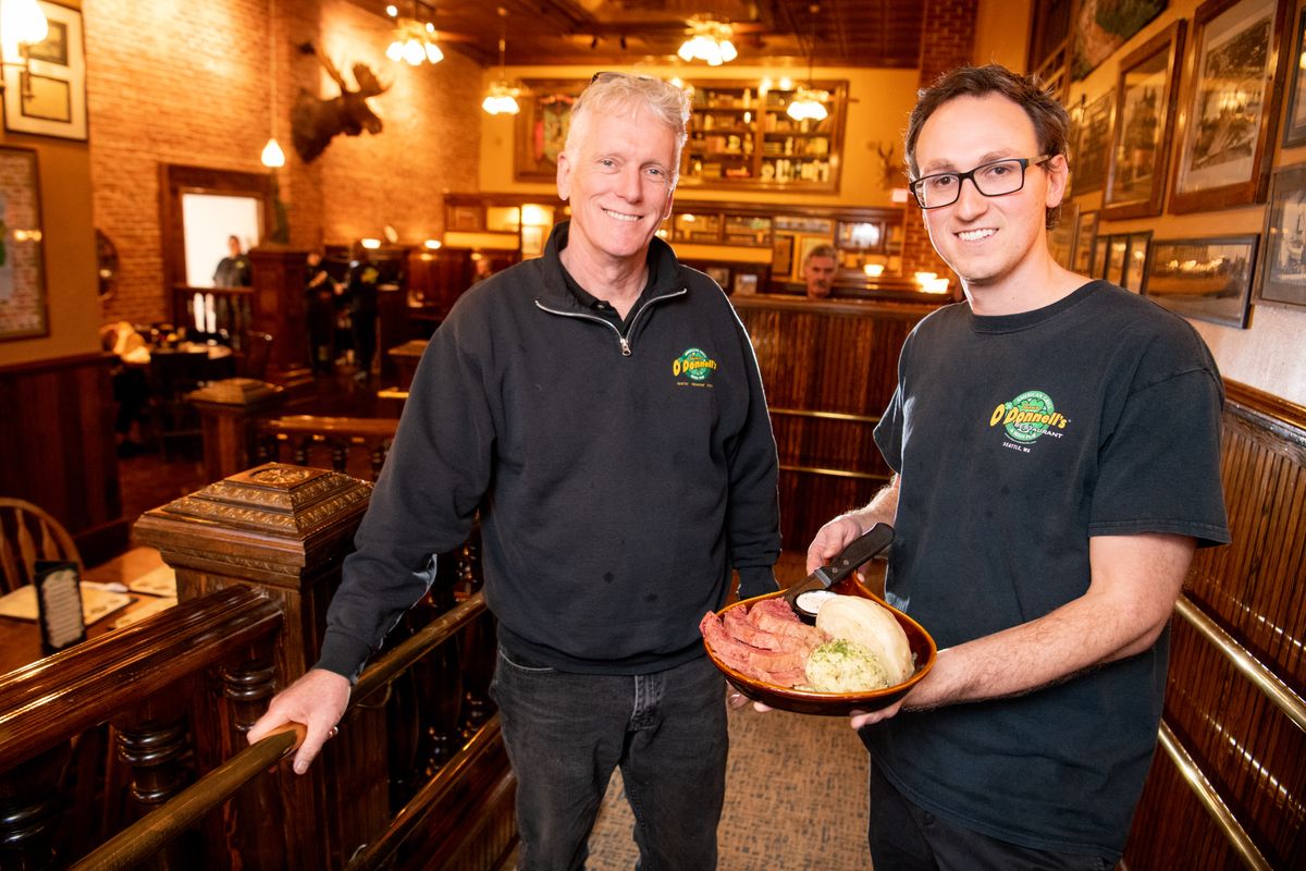 Owner Shawn O’Donnell and manager Chase Van Cotthem stand in the restaurant area at Shawn O’Donnell’s American Grill and Irish Pub in the building formerly occupied by Milford’s Fish House on Monroe Street at Broadway Avenue on Dec. 20, 2019. Van Cotthem is holding the restaurant’s corned beef and cabbage platter.  (Jesse Tinsley/The Spokesman-Review)
