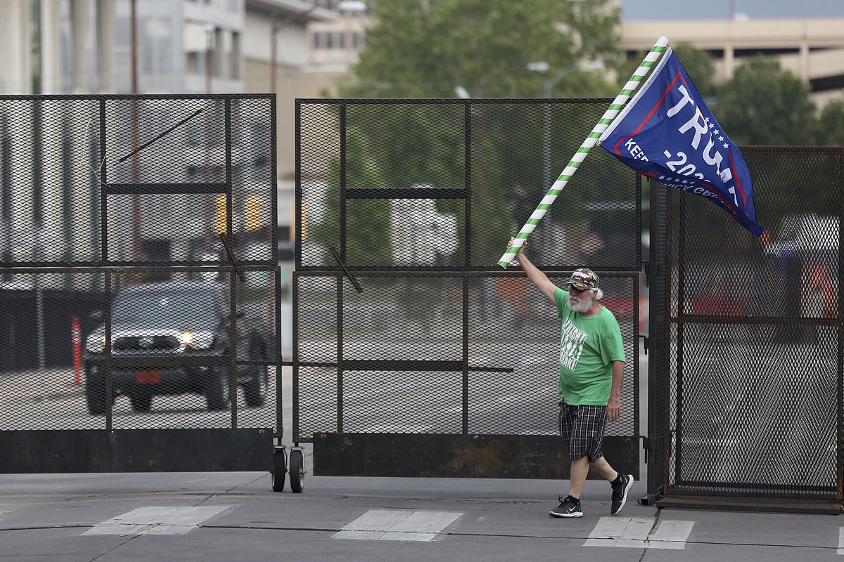 Mike Pellerin waves a Donald Trump campaign flag near a barricade in downtown Tulsa, Okla., ahead of President Donald Trump