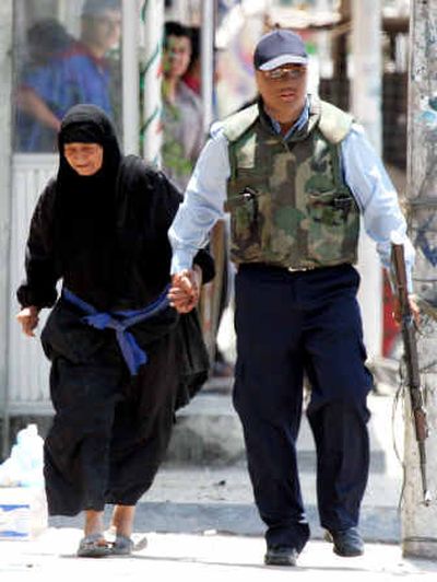 
A masked Iraqi policeman escorts a woman after a car bomb detonated in Baghdad on Friday. At least 825 people, including U.S. forces, have been killed since the new Shiite-led government was announced April 28. 
 (Associated Press / The Spokesman-Review)