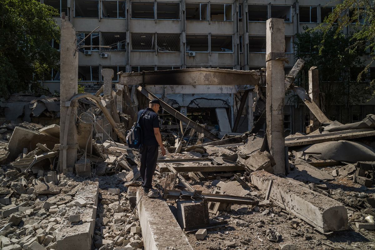A police officer stands in front of the National University of Shipbuilding, which was hit by a Russian missile on July 15.    (Wojciech Grzedzinski/For The Washington Post)