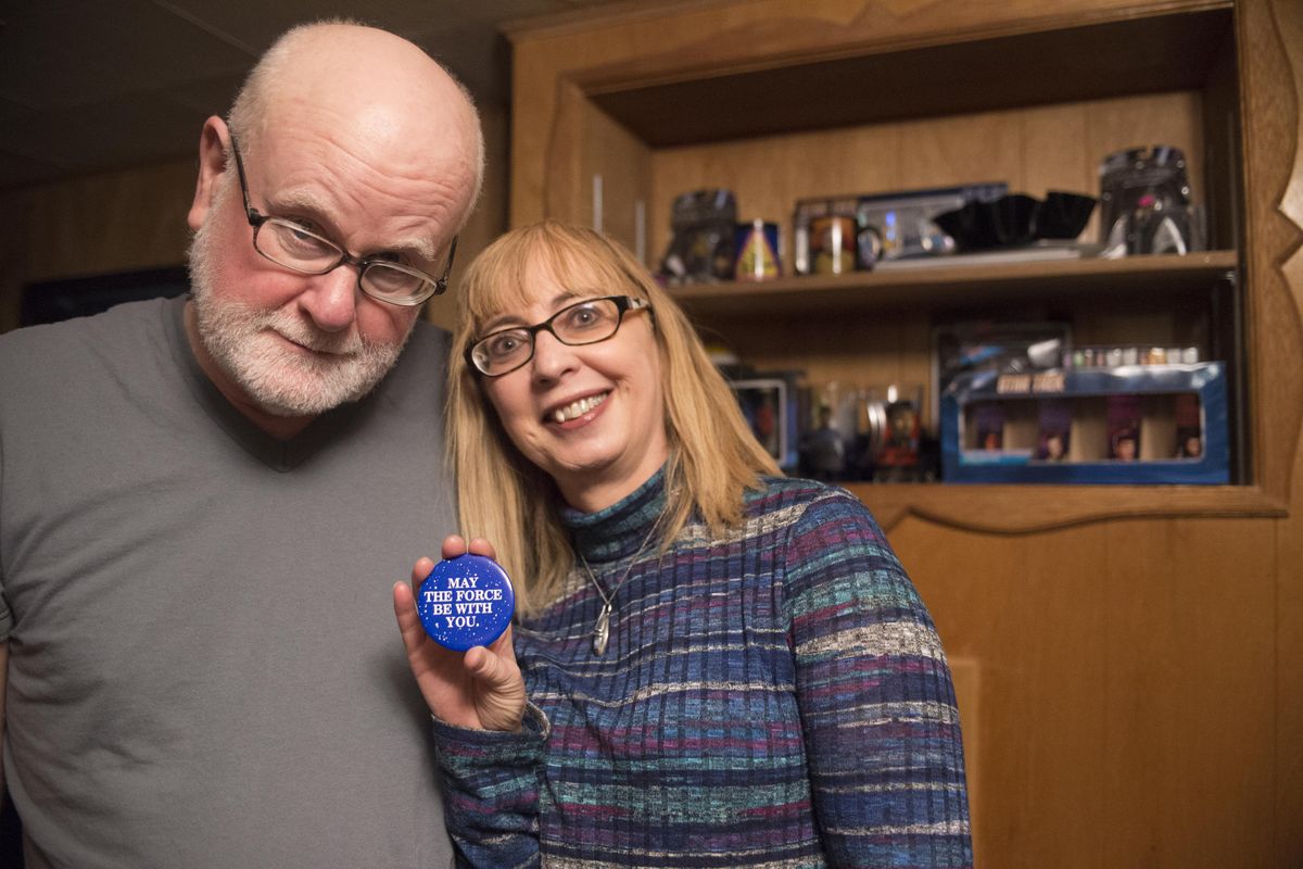 Michael Runyan and Marilyn Jackson Runyan have been bonding over their love of science fiction for 40 years, since seeing the original “Star Wars” in the theater. Pictured at their home Friday, May 26, 2017, Jackson Runyan is holding the button given away at the theater when they saw the movie. (Jesse Tinsley / The Spokesman-Review)