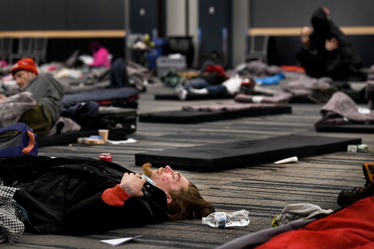 A man sleeps inside the Spokane Convention Center on Tuesday while seeking shelter from the freezing temperatures.  (Kathy Plonka/The Spokesman-Review)