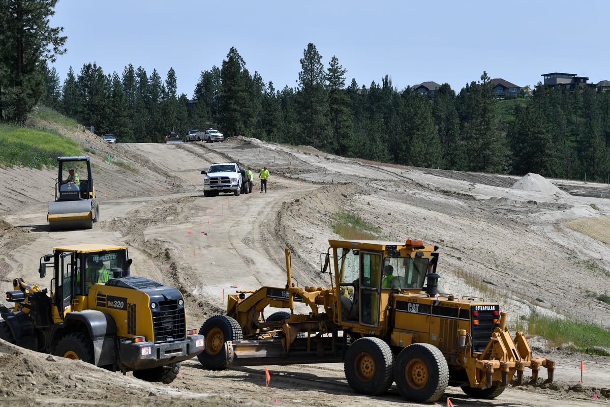 Construction crews work to grade hills for the eventual construction of 138 homes on 70 acres of land above Woodridge Elementary School on Thursday near Five Mile.  (TYLER TJOMSLAND)