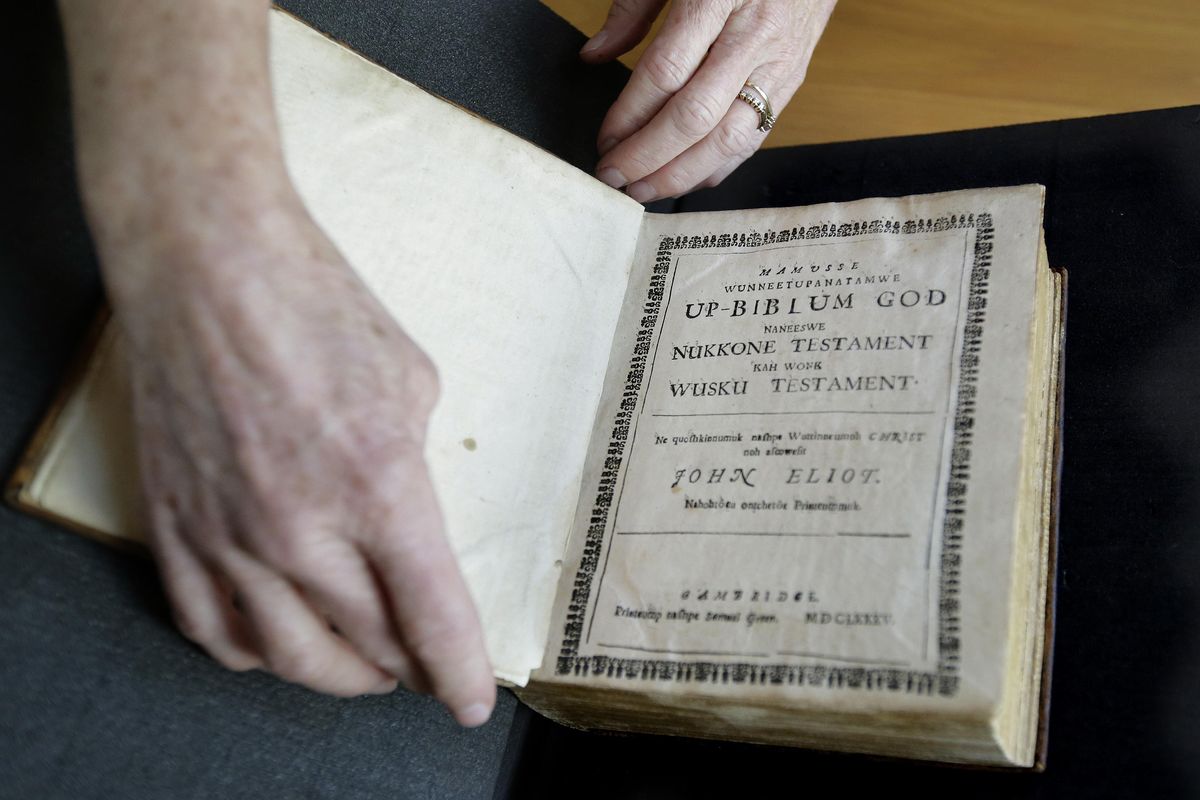 In this Thursday, Oct. 19, 2017, photo Massachusetts Institute of Technology archivist Nora Murphy places a second edition of the Eliot Indian Bible on a table at the MIT rare book collection, in Cambridge, Mass. The second edition of the Eliot Indian Bible, translated into Wampanoag, is dated 1685. Experts have relied on extensive written records in Wampanoag to reclaim the language, including 17th century phonetic translations of the King James Bible. (Steven Senne / Associated Press)