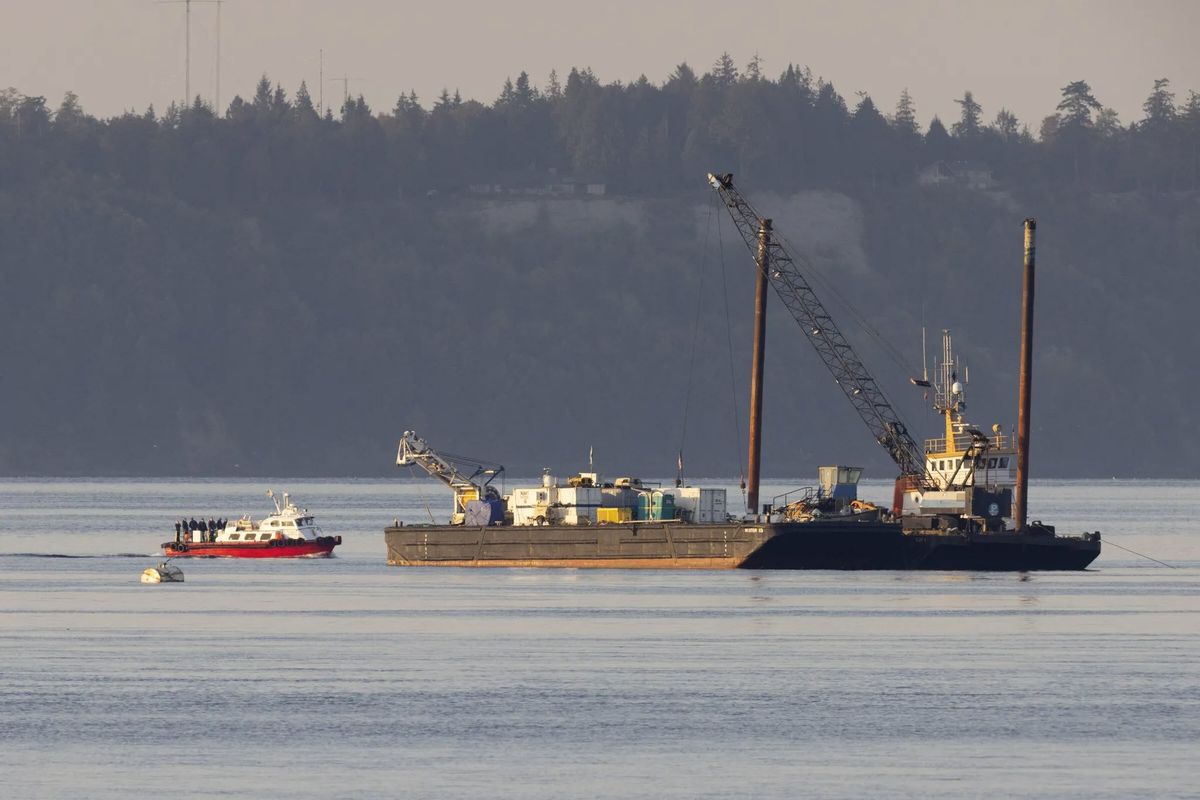 A pilot boat holding work crews approaches a barge as floatplane wreckage recovery continues in Mutiny Bay on Tuesday, off the west coast of Whidbey Island.  (Karen Ducey/Seattle Times)