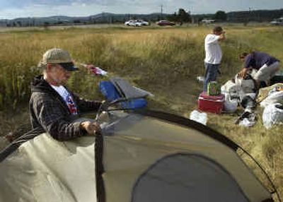 
Homeless campers Dave Bilsland, left, Joseph Day and Tony Prentice, right, pack their belongings Saturday morning after spending Friday night sleeping on the infield of the former Playfair racetrack. The men complied with a Spokane Police Department request to vacate the area by 8 a.m. Saturday. 
 (Dan Pelle / The Spokesman-Review)