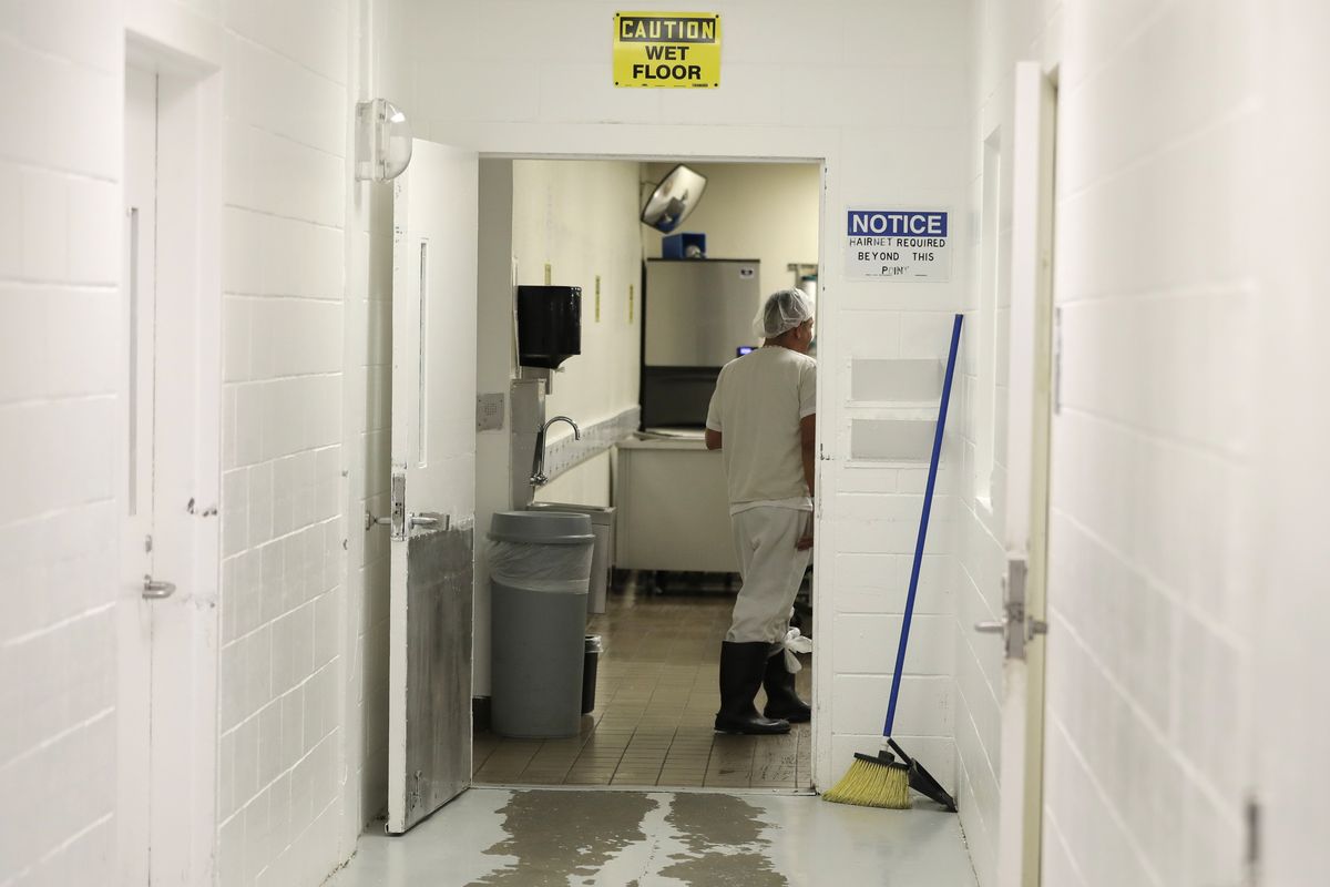 In this photo taken Sept. 10, 2019, a detainee works in a kitchen area at the GEO Group’s immigration jail in Tacoma, Wash., during a media tour. After nearly four years of litigation and pandemic-related delays, a federal jury on Tuesday, June 15, 2021, began deliberating whether the GEO Group must pay minimum wage to detainees who perform cooking, cleaning and other tasks at the facility – instead of the $1 per day they typically receive. (Ted S. Warren)