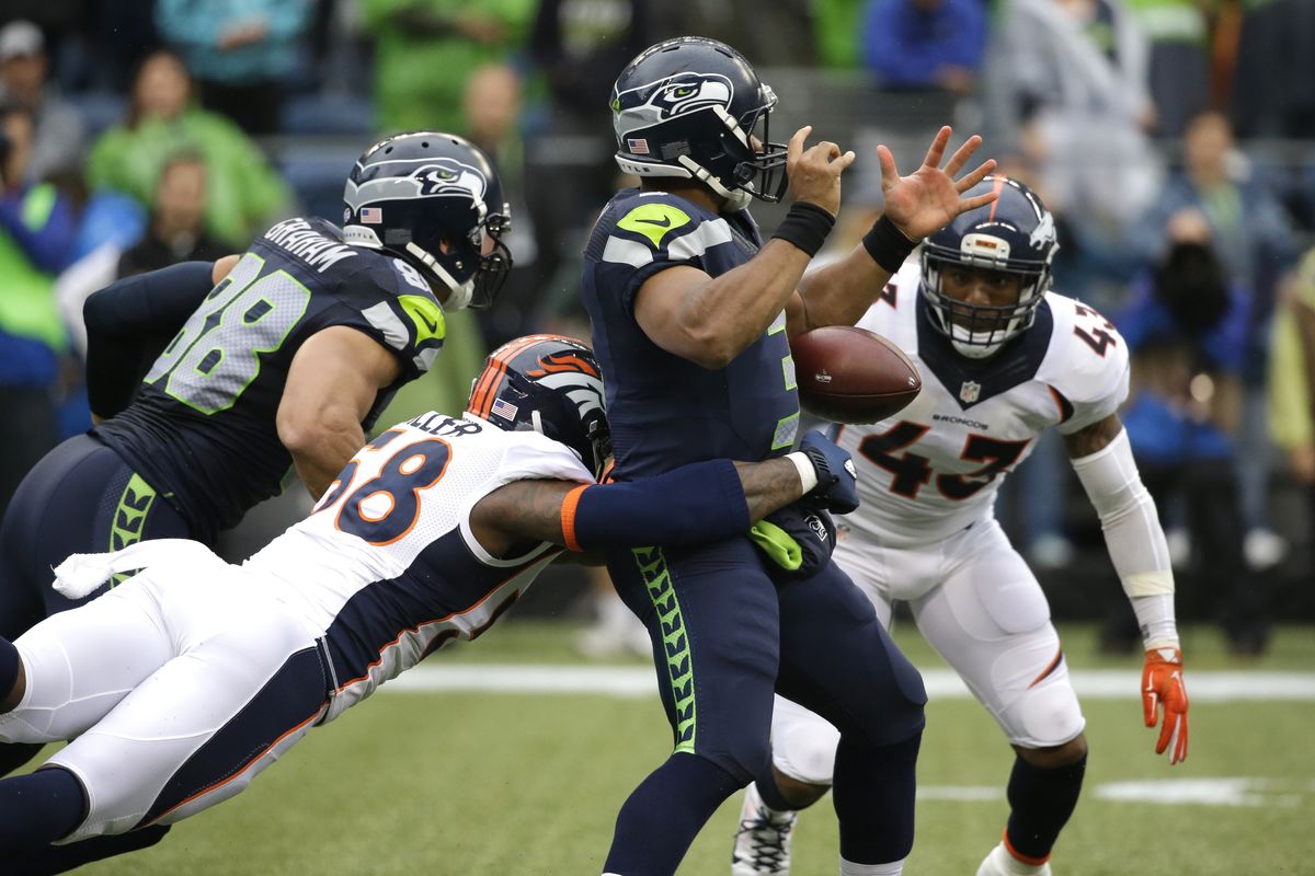 Seahawks quarterback Russell Wilson has the football stripped by Denver’s Von Miller in first-half action on Friday. (Associated Press)