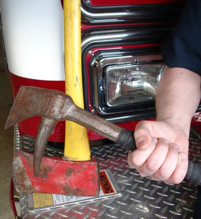 Spokane Valley firefighters use a Halligan tool and an ax, together called “the irons,” to crack a safe for police.  (John  Craig / The Spokesman-Review)