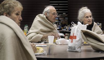 Pat Milton, left, and Keith and Gina Stacchino watch news reports Friday about the wildfire that forced them to spend the night in the Red Cross shelter at University High School. (Christopher Anderson / The Spokesman-Review)