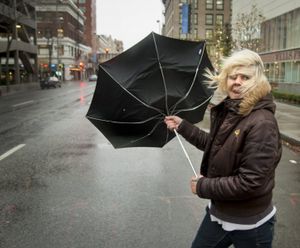 During a strong gust of wind, Michele Purkey's umbrella flips back as she crosses the intersection of First Avenue and Wall Street in downtown Spokane, Wash. (SR file photo)