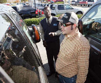 
Eric Anderson, front, of Aurora, Colo., joins his wife, Denise, center, in looking at the sticker price of a 2006 Ford F250 4x4 crew cab pickup truck with the help of salesman Carmore Fuller at a Ford dealership in the southeast Denver suburb of Centennial, Colo., on Thursday. 
 (Associated Press / The Spokesman-Review)