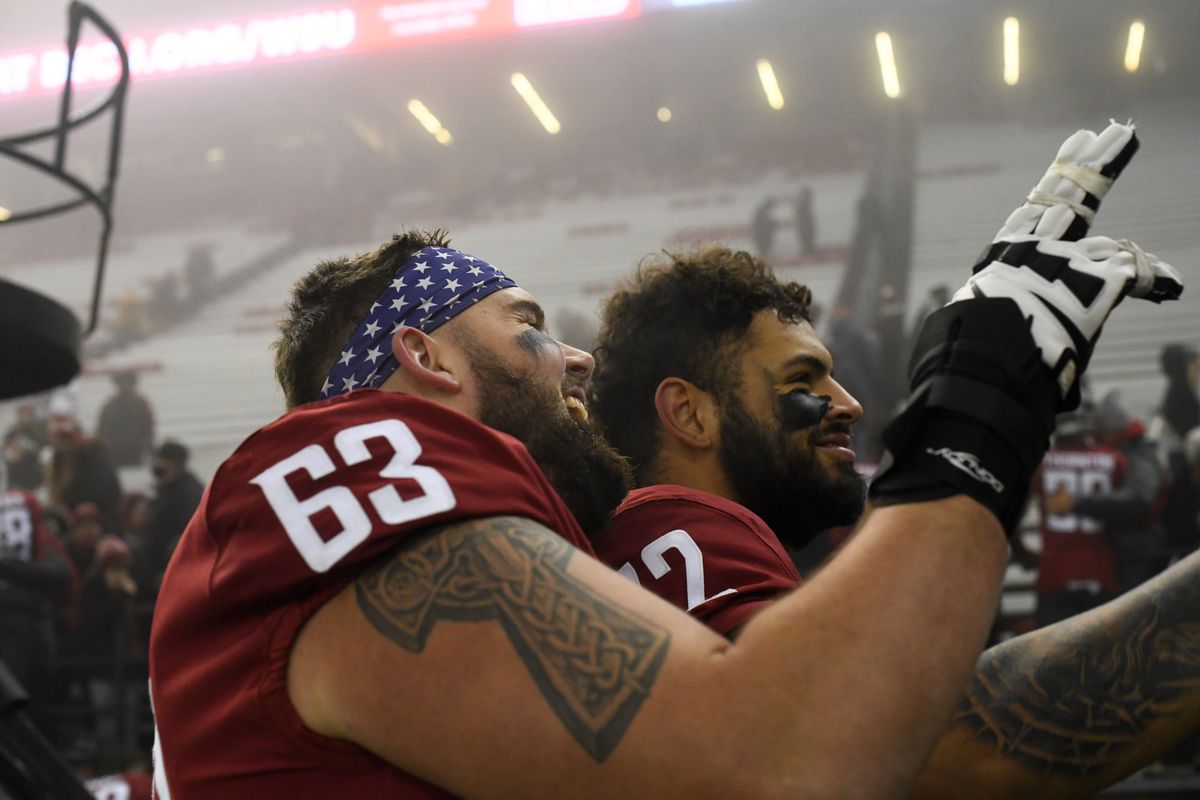 WSU’s Liam Ryan (63) and Abraham Lucas (72) gesture to cheering fans as they leave Martin Stadium Friday after the Cougars defeated Arizona.  (Tyler Tjomsland/The Spokesman-Review)
