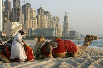 
A camel keeper waits for the tourists on the beach as the Jumeira Residences construction site looks in the background in Dubai, United Arab Emirates.  
 (Associated Press / The Spokesman-Review)