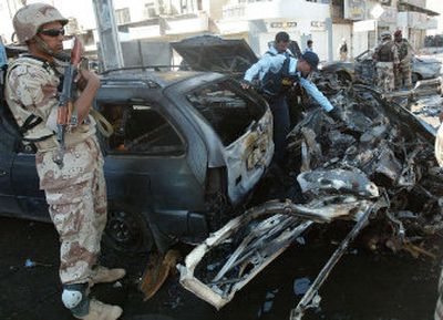 
An Iraqi policeman examines a destroyed vehicle at the scene of a attack in Baghdad, Iraq, on Sunday after a suicide car bomb hit two police vehicles in Al-Tahrir Square. 
 (Associated Press / The Spokesman-Review)