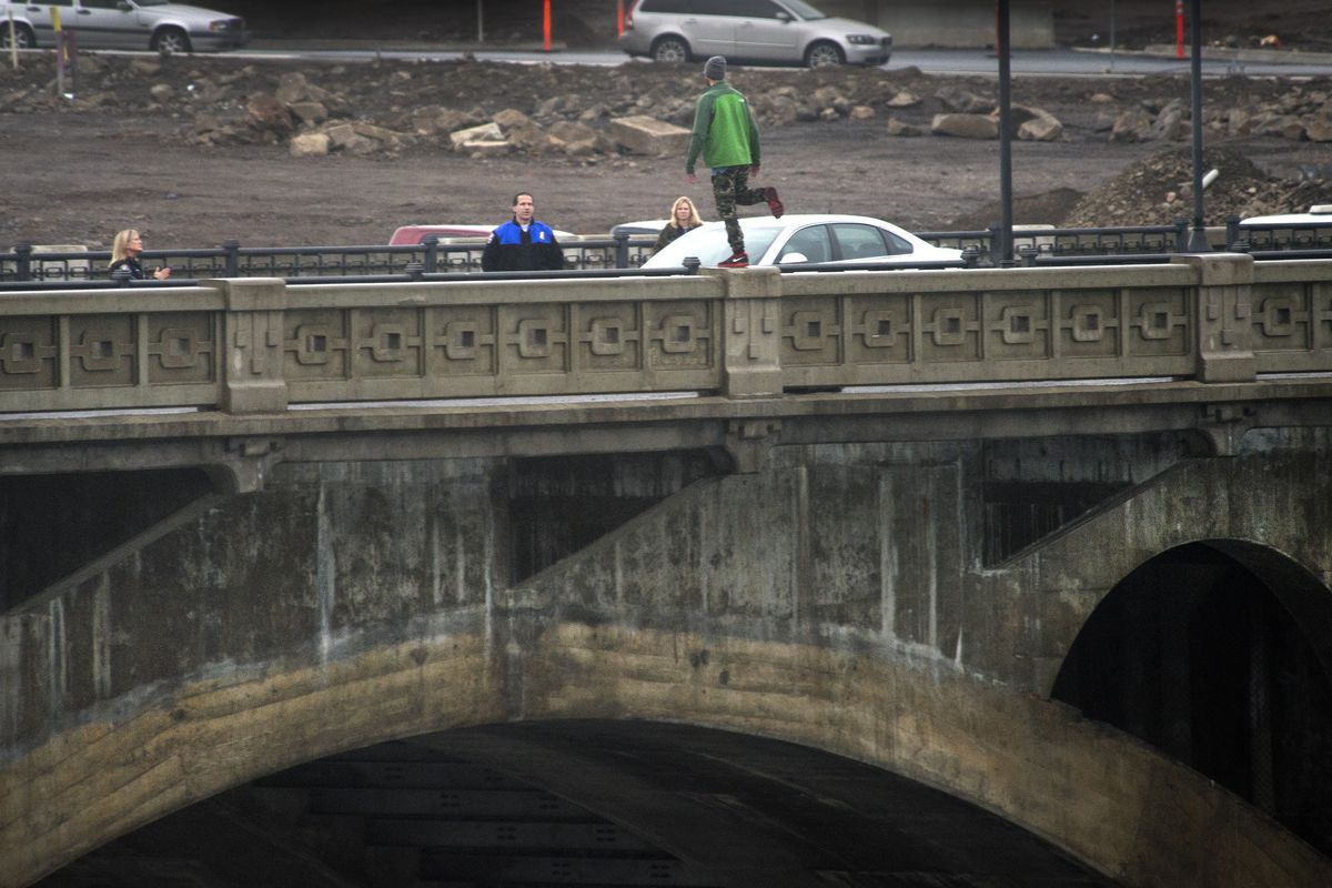 Spokane police Capt. Joe Walker talks with a man balancing on the rail of the Monroe Street Bridge on Thursday in downtown Spokane. After about 90 minutes, officers persuaded the man to step down. (Dan Pelle)