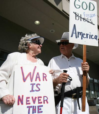 
Loyd Bliss, a retired Methodist pastor, and his wife, Patti, hold signs during a protest against Cheney's visit. 
 (The Spokesman-Review)