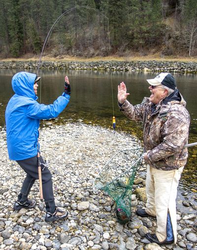 Marcia Trussell goes in for a high-five with Ted Mordhorst after she reeled in a steelhead that Mordhorst was able to net while fishing on the Clearwater River nearby Dworshak Dam on June 5 in Ahsahka.  (August Frank/Lewiston Tribune)