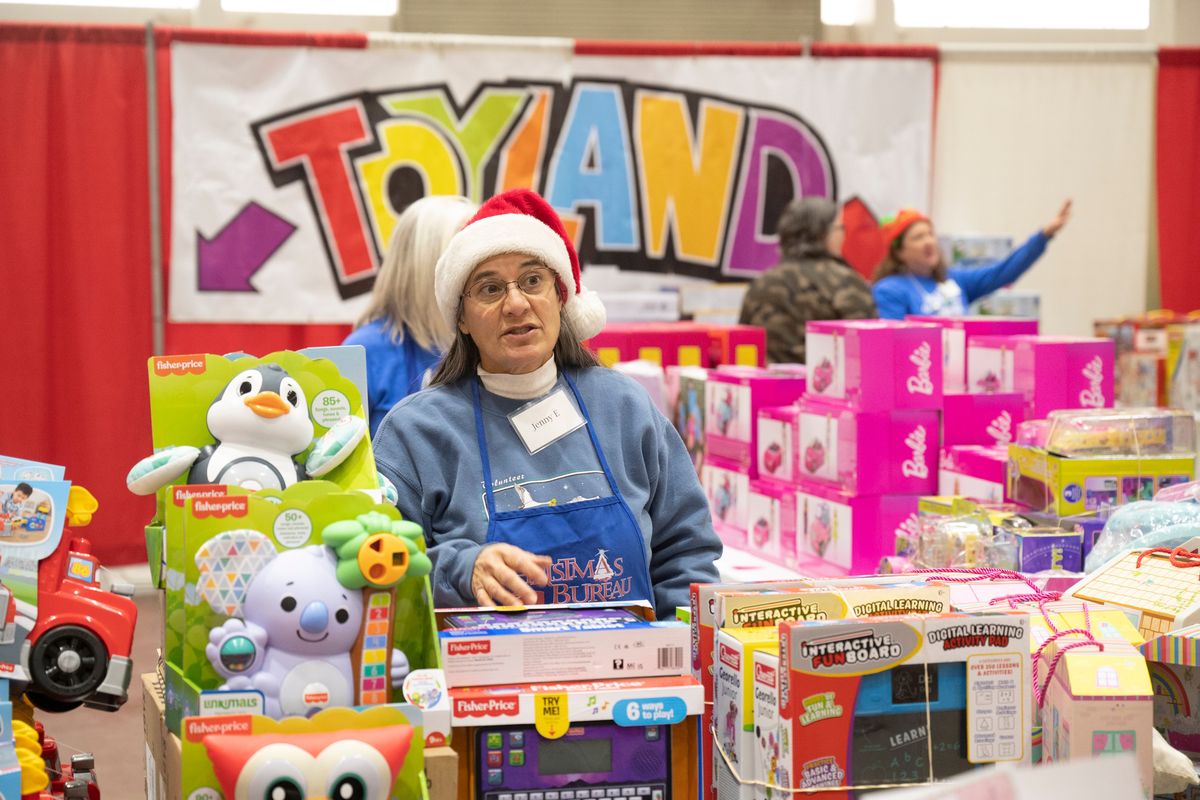 The Christmas Bureau’s Jenny Edgren directs Christmas Bureau clients to the correct displays of toys for each client’s needs Thursday Dec. 8, 2022, the first day open for the Bureau at the Spokane County Fair and Expo Center in Spokane, Washington. (Jesse Tinsley/The Spokesman-Review)