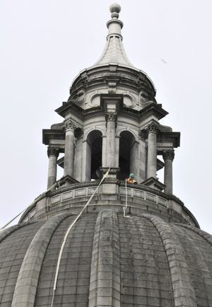 OLYMPIA -- Worker atop the Capitol Dome eases a rope down the side as the state prepares for a major cleaning project of the Legislative Building. (Jim Camden)
