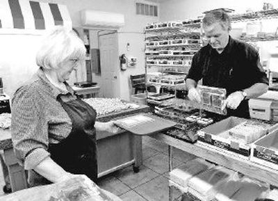 
Carolyn Rosanova watches her husband, Richard, press two custom candy bars out of a mold at their shop, the Wild Idaho Chocolate Co., on Wednesday.  The candy bars, below, are for the Great West Gym Fest this weekend in Coeur d'Alene. 
 (Photos by JESSE TINSLEY / The Spokesman-Review)