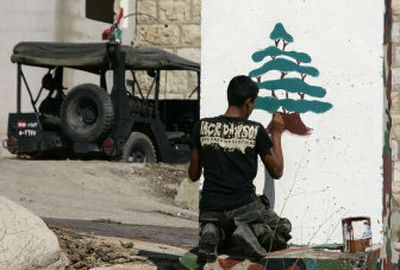 
A Lebanese soldier paints the cedar tree of the Lebanese flag on a checkpoint on the road in Kfar Kila, south Lebanon, near the border with Israel, on Wednesday. 
 (Associated Press / The Spokesman-Review)