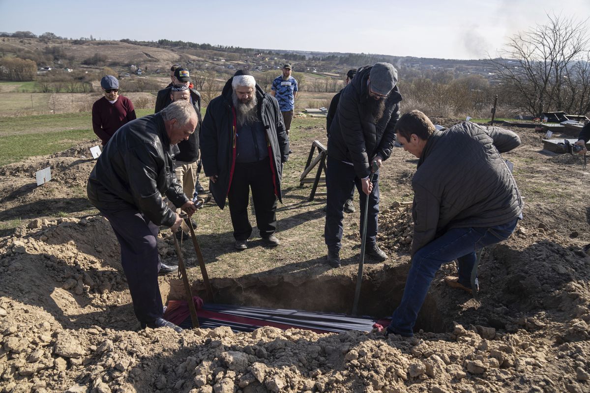 Funeral workers lower the coffin of Zoreslav Zamoiskiy, killed by Russian troops in the town of Bucha as Moshe Reuven Azman, Rabbi of Ukraine stands in center at the Jewish cemetery near Vasylkiv, Ukraine, on Friday, April 15, 2022. The final hours before Passover found the chief rabbi for Kyiv and Ukraine in a cemetery. Before he could mark the Jewish people’s escape from slavery in Egypt thousands of years ago, he was burying a man who didn’t escape a Russian bullet. (Evgeniy Maloletka)