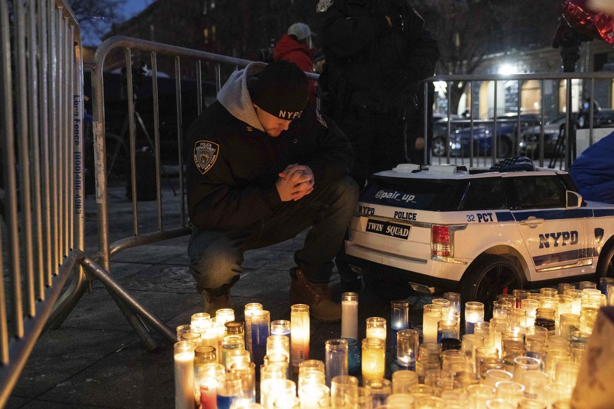 A police officer prays at a makeshift memorial outside the New York City Police Department