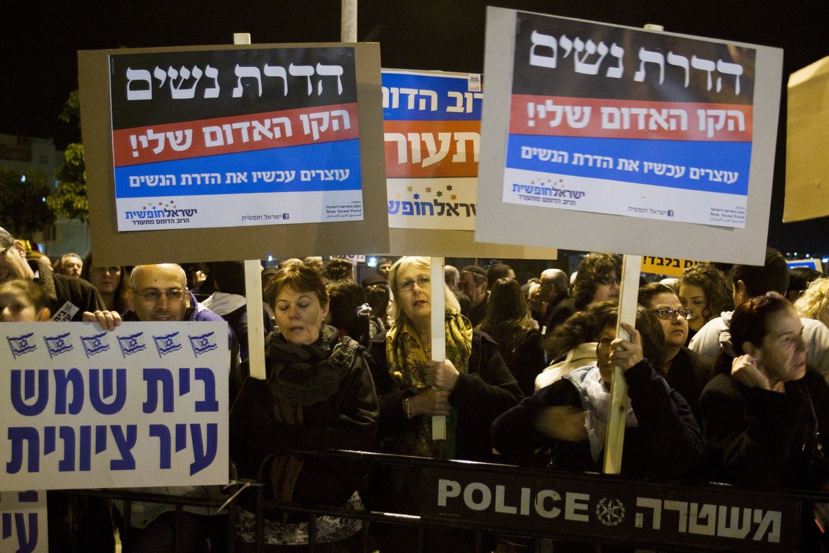Israelis hold up signs reading in Hebrew: “Gender segregation is my red line, stop gender segregation now” and “Beit Shemesh is a Zionist town” in the central Israeli town of Beit Shemesh on Tuesday. (Associated Press)