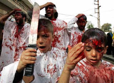 
As part of the Shiite festival of Ashoura, a Lebanese boy hits his head with a sword while others hit their bleeding heads with their hands Saturday in Nabatiyeh, Lebanon. Ashoura commemorates the death of a grandson of the prophet Muhammad, Imam Hussein, who was beheaded in Karbala, Iraq.
 (Associated Press / The Spokesman-Review)