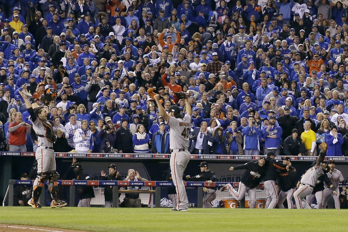 A sea of blue-clad Kansas City Royals fans can only watch as Giants catcher Buster Posey and pitcher Madison Bumgarner celebrate after the final out of Game 7. (Associated Press)