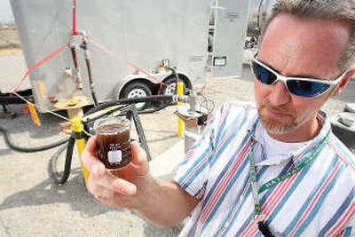 
Pacific Northwest National Laboratory research engineer Vince Vermeul holds a mixture of molasses and water that is being pumped into a well in Hanford on Thursday.  Tri-City Herald
 (Paul T. Erickson Tri-City Herald / The Spokesman-Review)