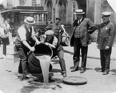 New York City Deputy Police Commissioner John A. Leach, right, watches agents pour liquor into sewer following a raid circa 1921.