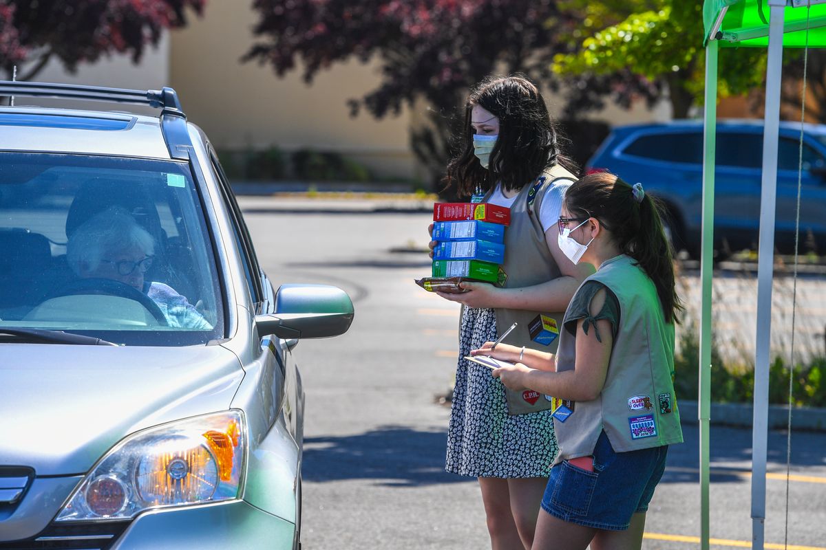 Girl Scout Troop 5161 members Taylor Jensen and Abi Breckon, right, take and deliver an order of cookies during a drive-thru event, Friday, June 19, 2020 at the Shopko parking lot on south Regal Street in Spokane. Four booths were set up to try and sell 6000 boxes of cookies. They will try again on Staurday at the same location.  (DAN PELLE/THE SPOKESMAN-REVIEW)