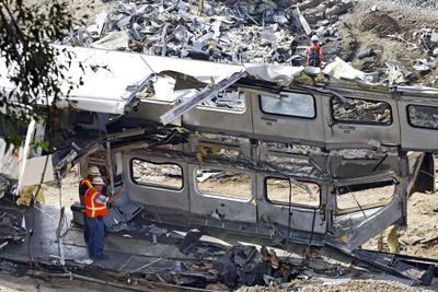 Investigators photograph the mangled inside of a Metrolink commuter train in Chatsworth, Calif., on Sunday. At least 25 people were killed or have died from injuries  in the Friday collision of a Metrolink commuter train and a freight train in the San Fernando Valley. At least 135 people were injured in the crash.  (Associated Press / The Spokesman-Review)