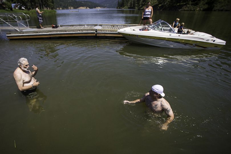 Franco Barnhart, left, visits with his business partner Tony Russo as they take a dip Monday near the boat launch of Fernan Lake. The Panhandle Health District and the Idaho Department of Environmental Quality issued a warning of high levels of blue-green algae in the lake that may be harmful. (Shawn Gust/press)