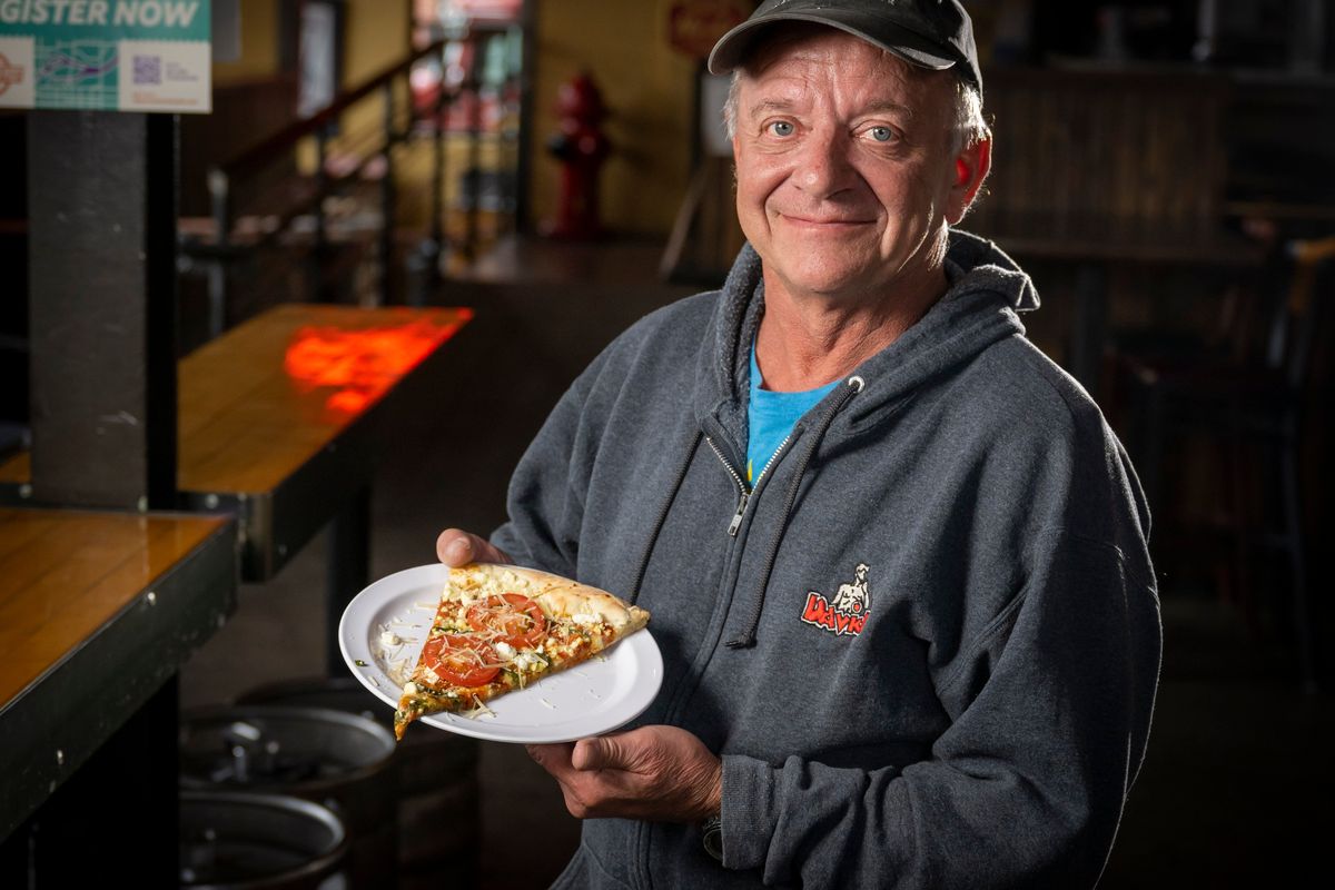 A customer favorite at David’s Pizza, owner Mark Starr holds a slice of the DaVinci made with feta, pesto, sliced tomatoes, garlic, red sauce and mozzarella. Starr said he made a salmon pizza 15 years ago, but customers at the time were not fans.  (COLIN MULVANY/THE SPOKESMAN-REVI)