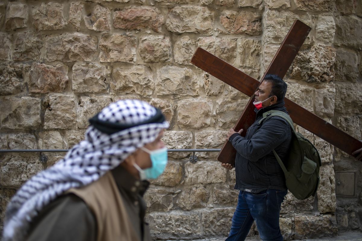 A Christian carries a cross as he walks along the Via Dolorosa towards the Church of the Holy Sepulchre, traditionally believed by many to be the site of the crucifixion of Jesus Christ, during the Good Friday procession in Jerusalem’s old city, Friday. (Ariel Schalit)