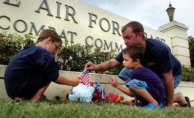 Staff Sgt. Matt Shomo and his sons Matthew, 5, right, and Jacob, 7, place flowers at the entrance to the north gate of Barksdale Air Force Base on Wednesday in Bossier City, La., to honor the airmen who died in a B-52 crash Sunday.  (Associated Press / The Spokesman-Review)