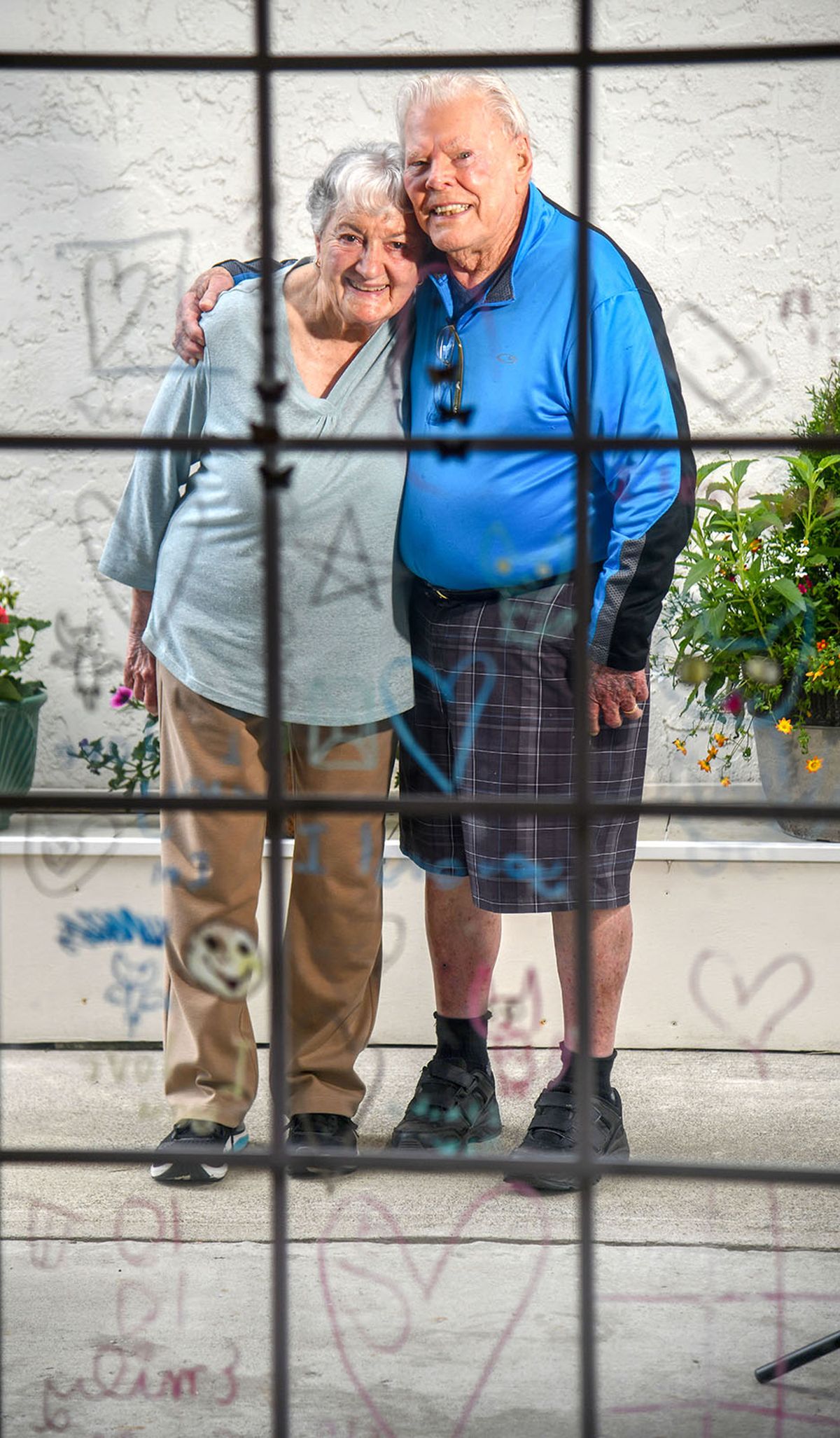 Victoria and Robert Logan, standing outside on their patio, are framed by drawings made by their great-granddaughter, Emily Frey, on the slider glass. The couple will celebrate their 77th wedding anniversary this fall.  (DAN PELLE/THE SPOKESMAN-REVIEW)