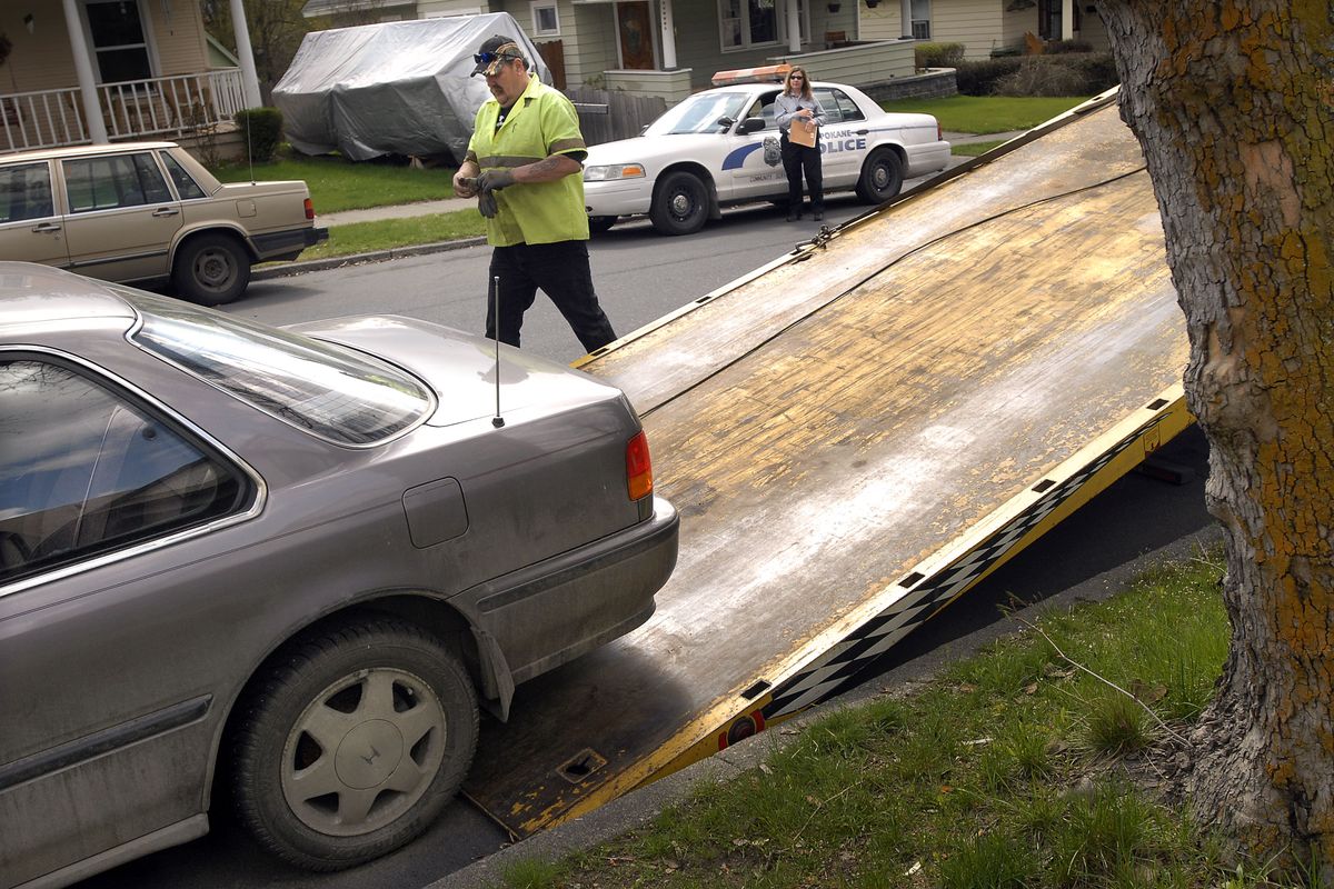 Community Services Officer Becky Nelson watches as Dino Hepburn of Bulldog Towing loads a Honda onto a flatbed truck on April 19, 2007, after Nelson noticed the abandoned car along Augusta Street on the northside of Spokane. Nelson ran the plates and the car was listed as a stolen vehicle.   (BRIAN PLONKA)