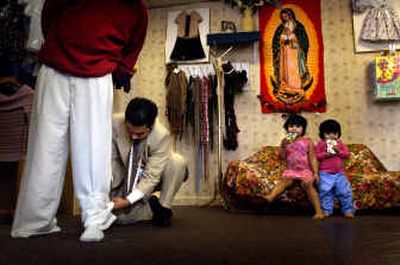 
Alex Figueroa, 26, works on a hem while his daughters, Rosita, 4, and Elizabeth, 3, drink juice in their shop on East Ermina Avenue in northeast Spokane. Figueroa and his wife, Rosa, both had tailors as fathers. The couple, who also have twin baby boys, moved from California to Spokane to start their own shop and a new life.
 (Jed Conklin photos/ / The Spokesman-Review)