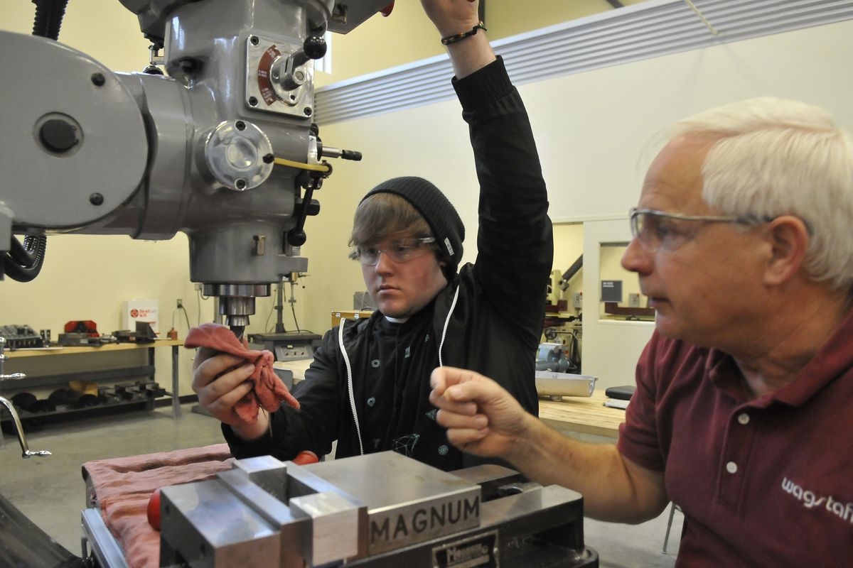 Tyler Saunders, a senior from Mead High School, gets tips on how to safely mount a new cutting tool on a milling machine from machinist Cal Christen at Spokane Community College on Oct. 25. (PHOTOS BY JESSE TINSLEY)